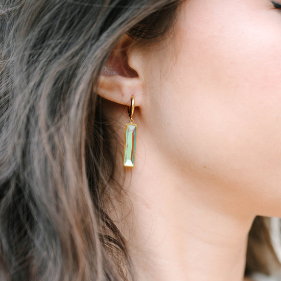 These minimalist bar earrings feature a sleek 5 x 20 mm stone set in a refined design, suspended from classic 12mm hoops. The elongated stone creates an elegant vertical accent, while the hoop silhouette offers versatile everyday wear. 