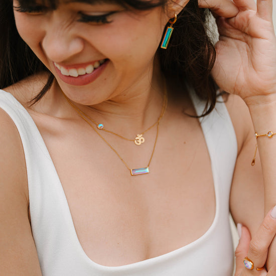 Woman wearing gold necklaces and earrings, smiling.