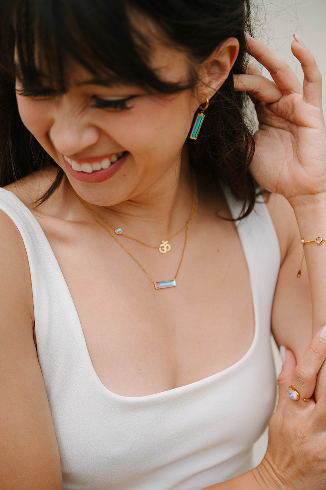 Woman wearing gold necklaces and earrings, smiling.