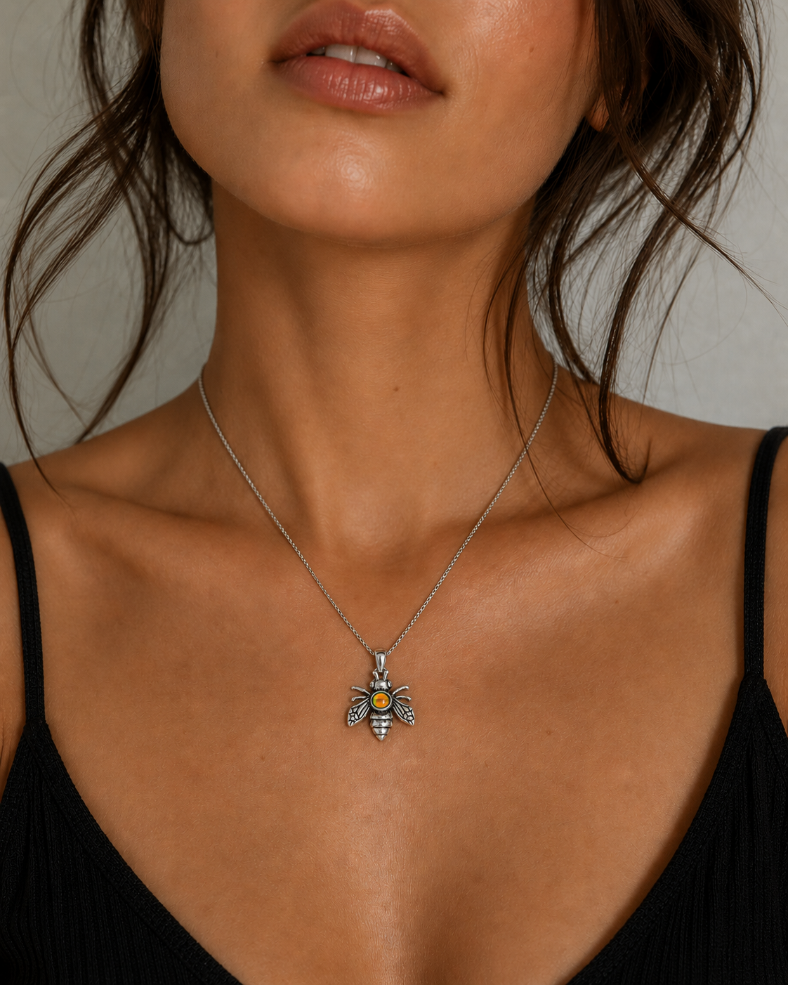 Necklace with a bee pendant worn by a model against a neutral background