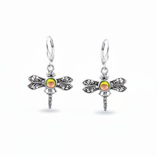 A pair of sterling silver dragonfly earrings with intricate details and a glowing crystal center.