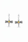 A pair of sterling silver dragonfly earrings with intricate details and a glowing crystal center.