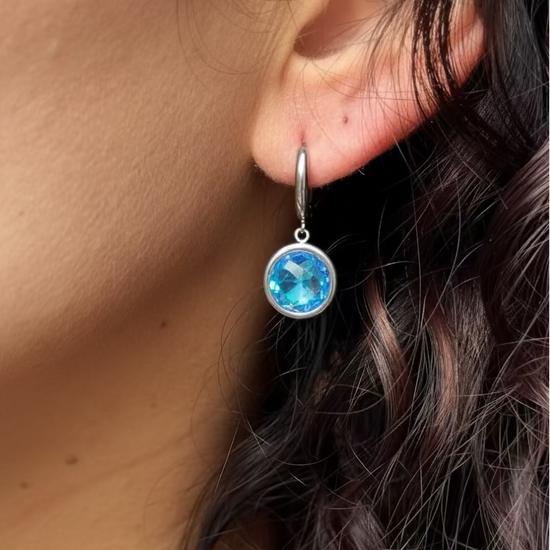 Close-up of a person wearing a blue earring with a blurred background