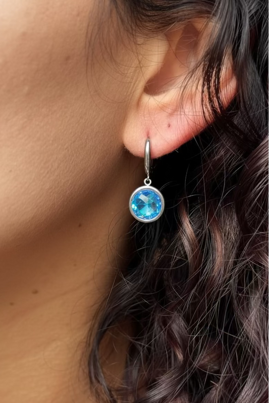 Close-up of a person wearing a blue earring with a blurred background