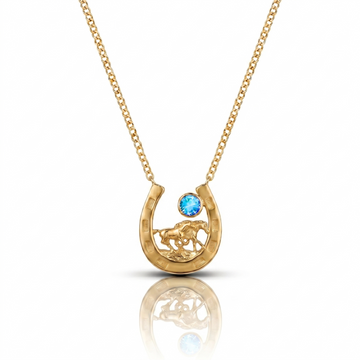 Gold necklace with a horseshoe pendant featuring a blue gemstone on a white background