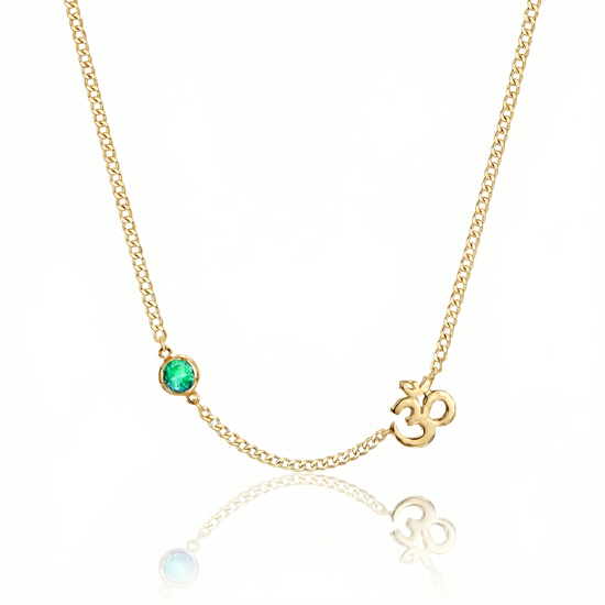 Gold necklace with a green gemstone and 'OM' symbol on a white background