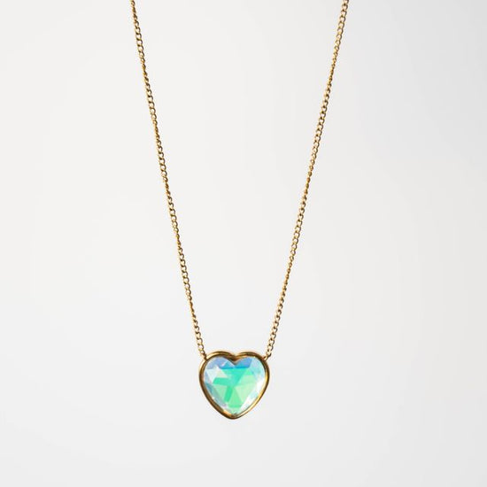 Heart-shaped opal pendant on a gold chain against a white background