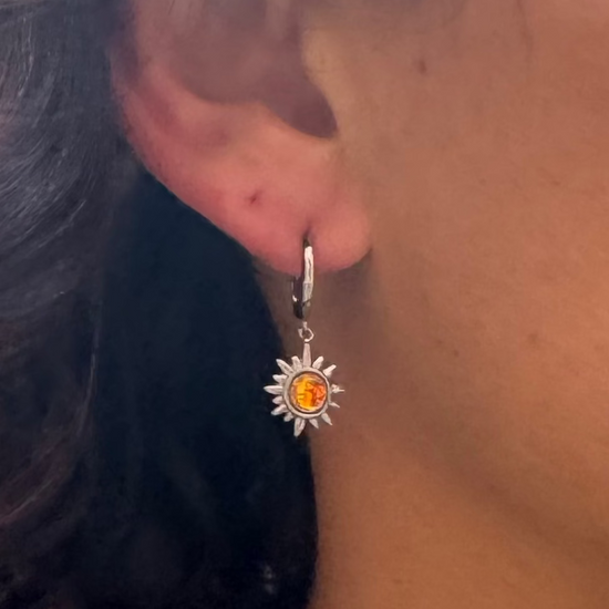 Close-up of a person wearing gold necklaces with colorful pendants and earrings.