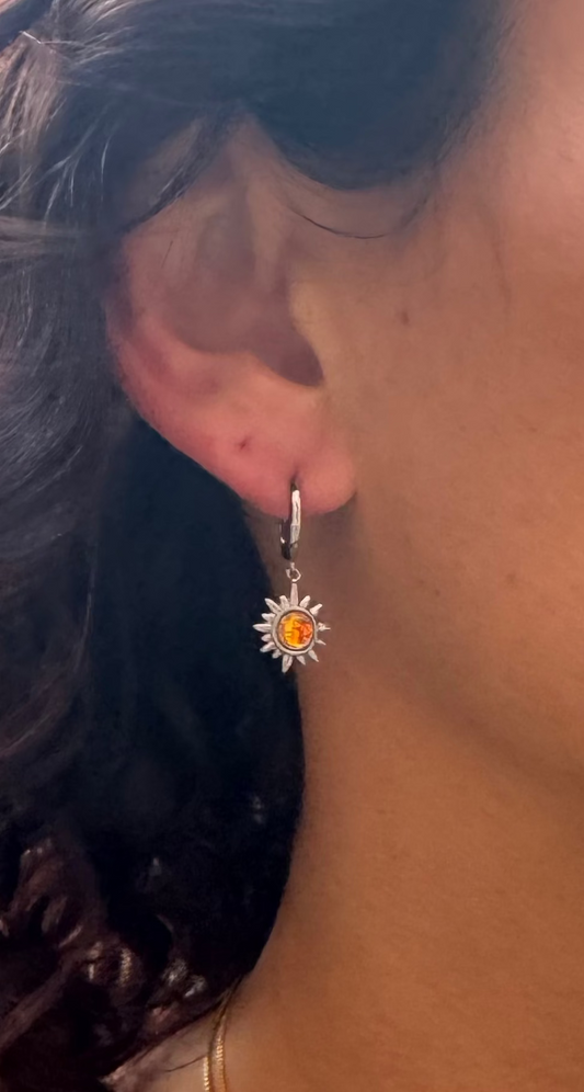 Close-up of a person wearing gold necklaces with colorful pendants and earrings.