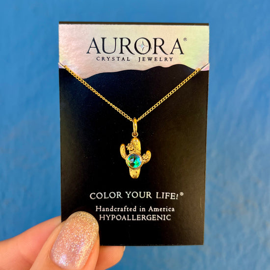 Gold necklace with a cactus pendant on an Aurora Crystal Jewelry card
