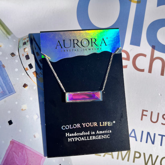 Silver necklace with a pink gemstone pendant on an Aurora Jewelry card 