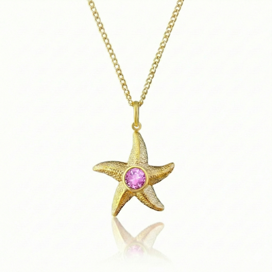 Gold starfish pendant with a pink gemstone on a gold chain