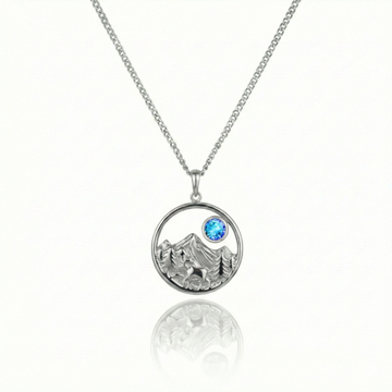 Silver necklace with a bear, mountain, and blue gem pendant.