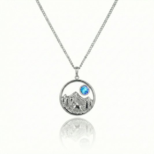 Silver necklace with a bear, mountain, and blue gem pendant.