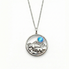 Silver necklace with a round pendant featuring a bear, mountains, and a blue gemstone.