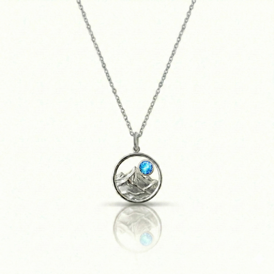 Silver necklace with a round pendant featuring a mountain and a blue gemstone.