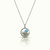 Silver necklace with a round pendant featuring a mountain and a blue gemstone.