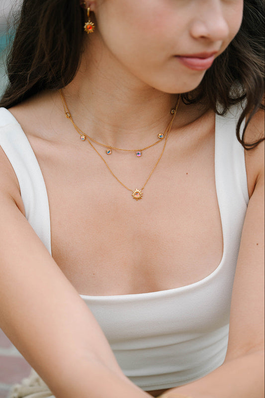 Woman wearing a gold sunburst necklace with a blurred background
