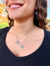 Close-up of a person wearing a delicate whale tale necklace with star earrings 