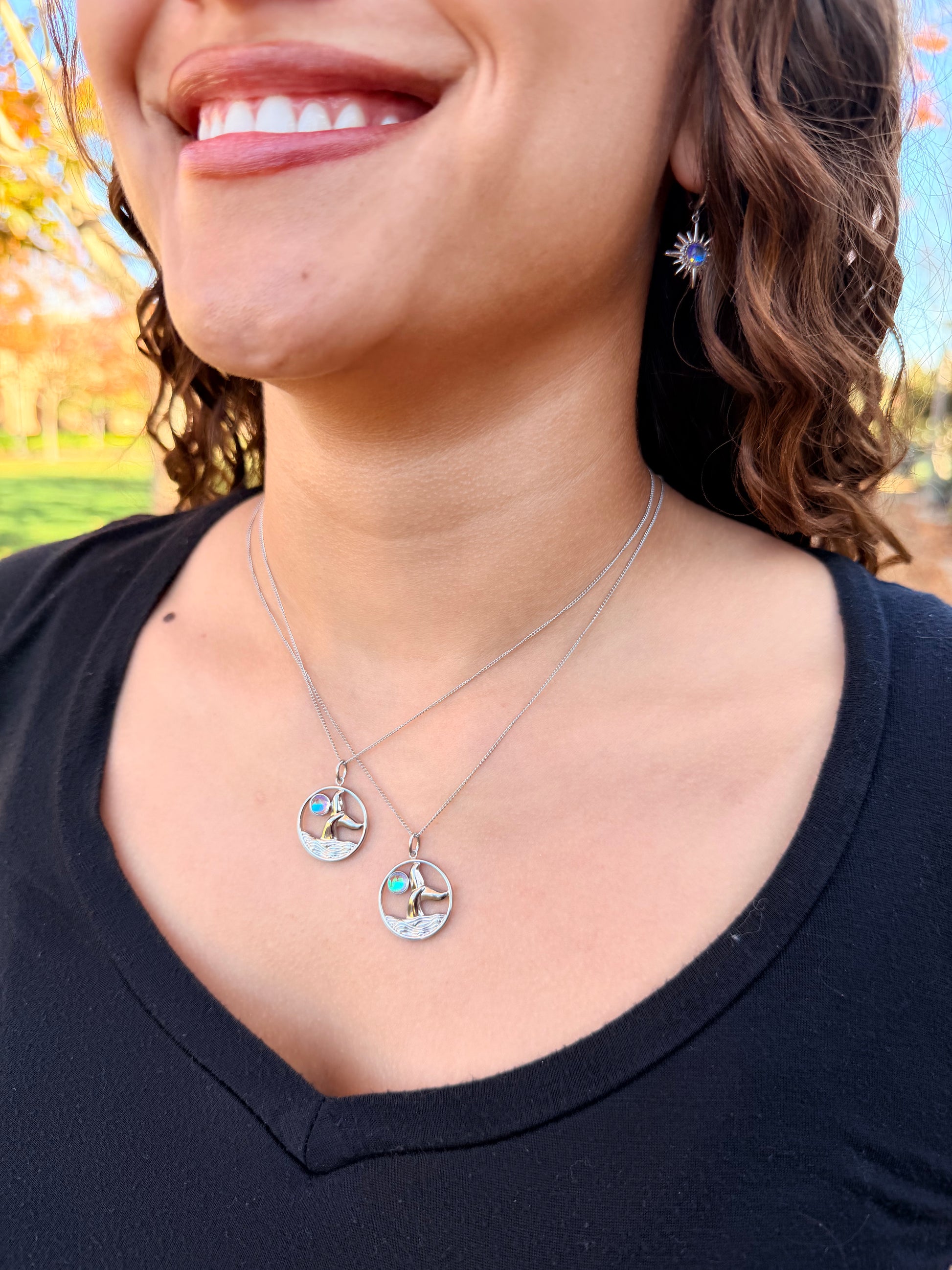 Close-up of a person wearing a delicate whale tale necklace with star earrings 