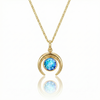 Gold crescent necklace with a blue gemstone pendant.