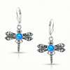 Sterling Silver Dragonfly Earrings feature a  polished blue glowing crystal delicately surrounded by intricate silver details in the wings and body of the dragonfly, creating a whimsical yet elegant look.