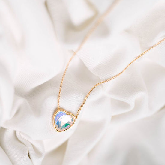Heart Crystal Necklace, a stunning symbol of love and elegance. This beautiful necklace features a radiant heart-shaped crystal, surrounded by a delicate halo of smaller crystals that enhance its brilliance. Designed to capture and reflect light, this necklace creates a sparkling effect that adds a touch of glamour to any outfit.