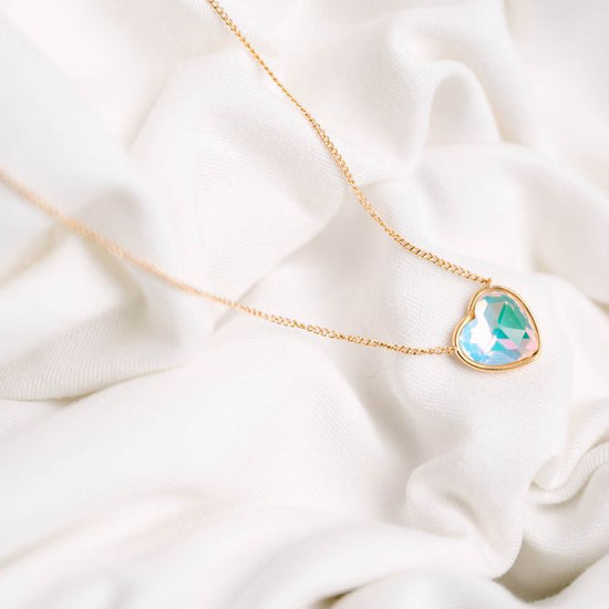 Heart Crystal Necklace, a stunning symbol of love and elegance. This beautiful necklace features a radiant heart-shaped crystal, surrounded by a delicate halo of smaller crystals that enhance its brilliance. Designed to capture and reflect light, this necklace creates a sparkling effect that adds a touch of glamour to any outfit.