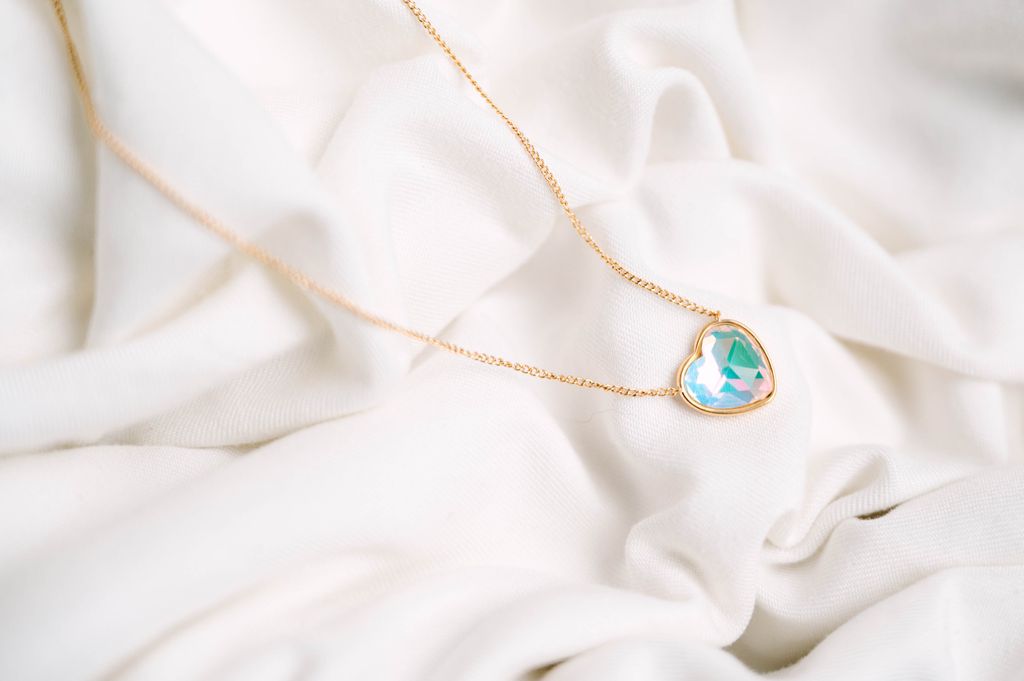 Heart Crystal Necklace, a stunning symbol of love and elegance. This beautiful necklace features a radiant heart-shaped crystal, surrounded by a delicate halo of smaller crystals that enhance its brilliance. Designed to capture and reflect light, this necklace creates a sparkling effect that adds a touch of glamour to any outfit.