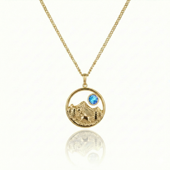Gold necklace with a moose, mountain, and blue gem pendant.