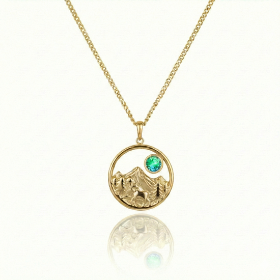 Gold necklace with a moose walking in medow, mountain, and green gem pendant.