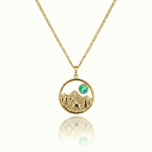 Gold necklace with a moose walking in medow, mountain, and green gem pendant.