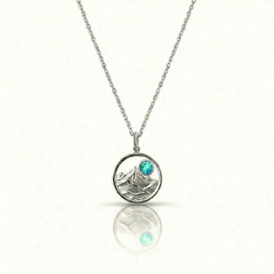 Silver necklace with a mountain pendant and a blue gemstone.