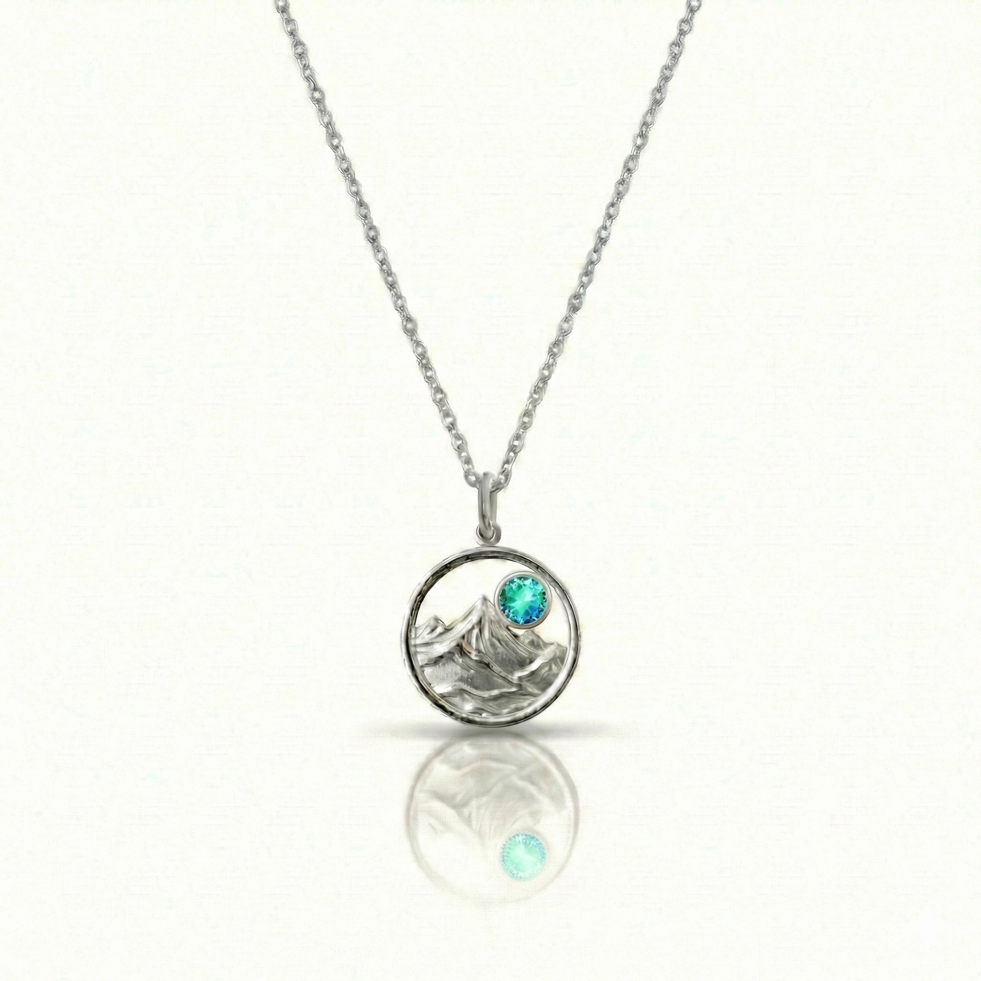 Silver necklace with a mountain pendant and a blue gemstone.
