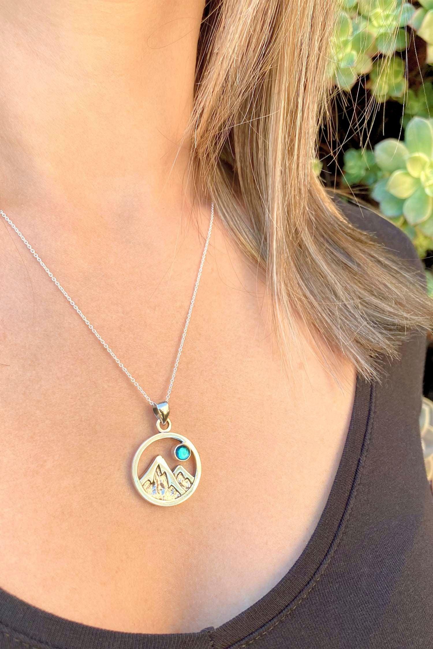 Mountain Pendant featuring a beautiful depiction of mountains under the moon or sun, this pendant captures the serene beauty of nature. The polished green pendant includes an 18" sterling silver .7mm box chain.