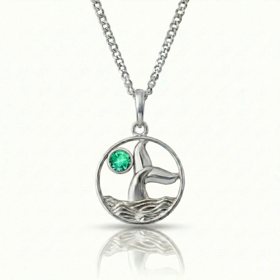 Whale tale pendant with silver stainless steel and a green gemstone.
