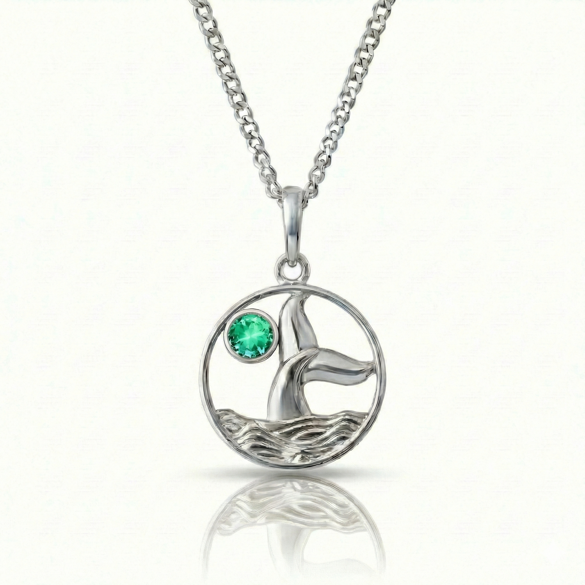 Whale tale pendant with silver stainless steel and a green gemstone.