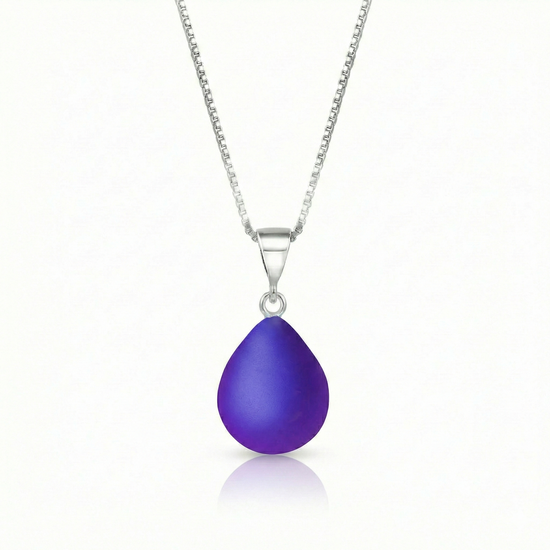 Our best selling crystal X-Small Drop Pendant is a beautiful, easy simple addition to any outfit. Handmade pendants come in a wide variety of colors and shine with an iridescent glow of color from within. Sterling silver .7mm box chain, 18" included with the frosted violet pendant.
