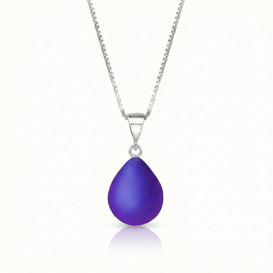 Our best selling crystal X-Small Drop Pendant is a beautiful, easy simple addition to any outfit. Handmade pendants come in a wide variety of colors and shine with an iridescent glow of color from within. Sterling silver .7mm box chain, 18" included with the frosted violet pendant.